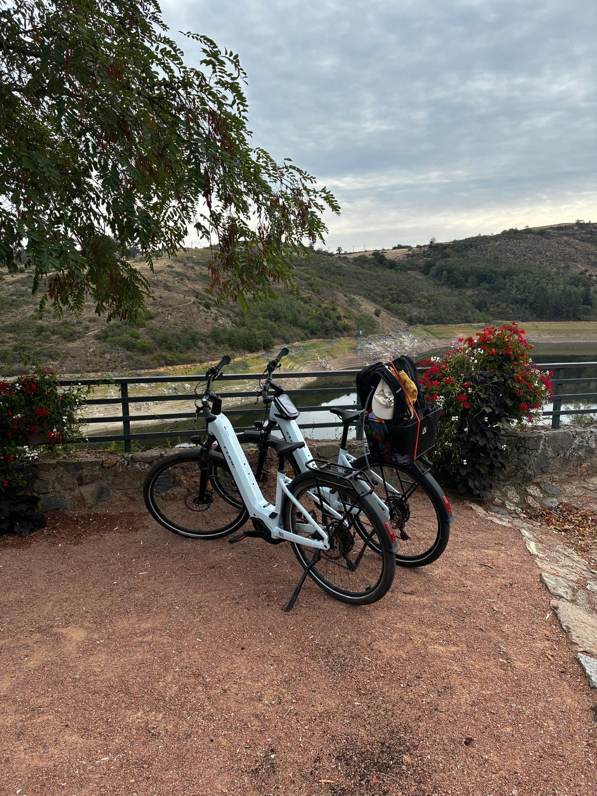 Deux vélos électriques garés au bord de l’eau, avec un panier