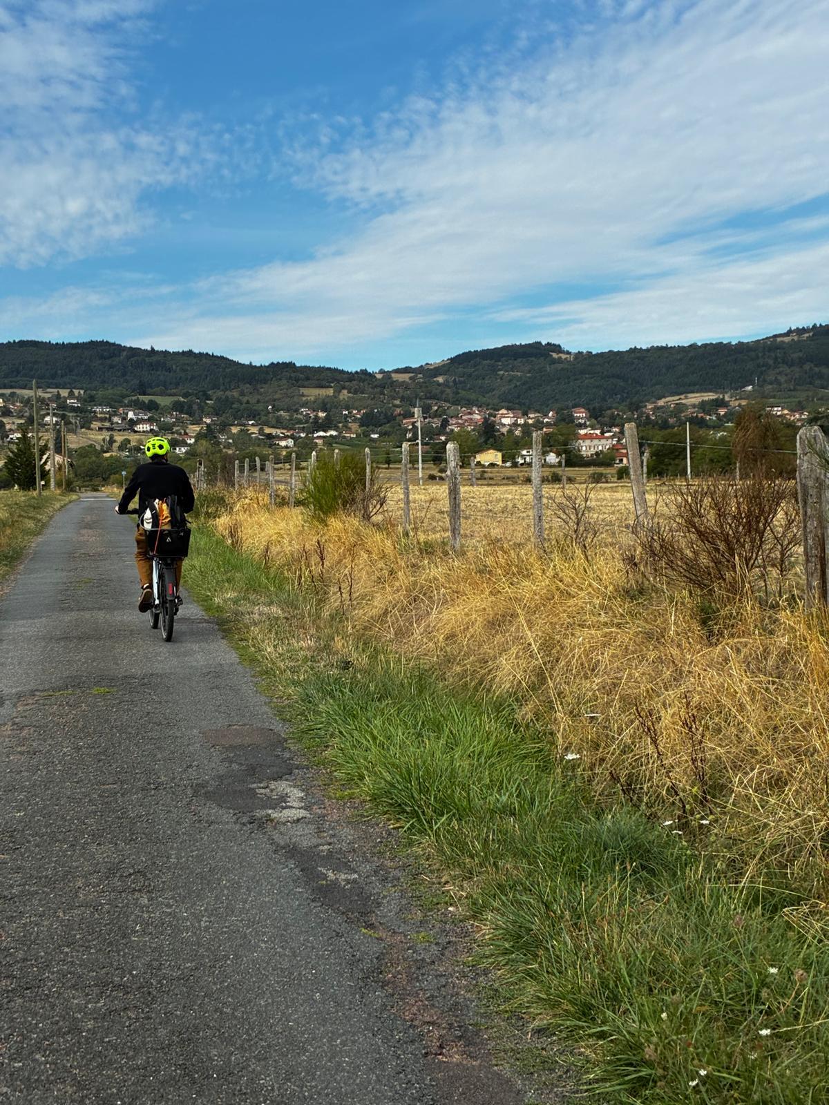Cycliste sur une petite route de campagne, sacoche à l’arrière